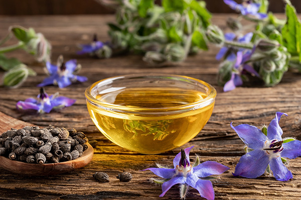 Omega-6 Fettsäuren, Öl steht auf dem Tisch, violette Blüten liegen rund herum